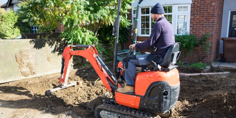 white caucasian male ground working in a small orange digger picture id619629778