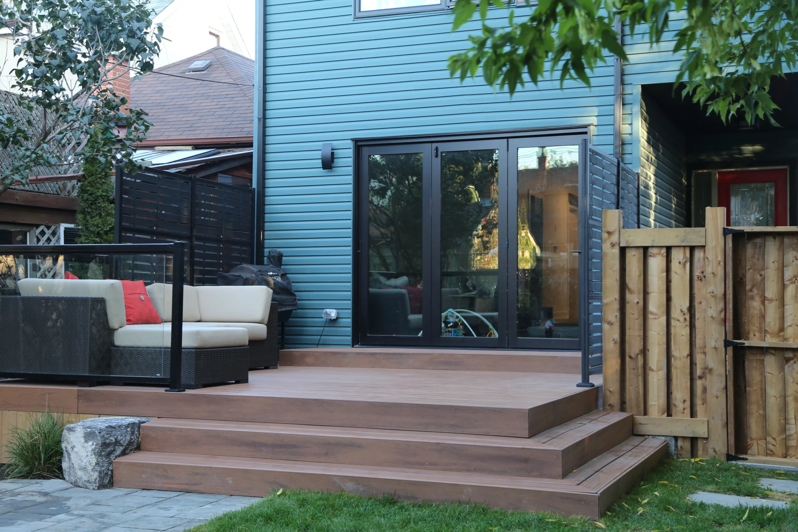 Low maintenance composite deck with wide steps, glass railing, and outdoor sectional at a modern home